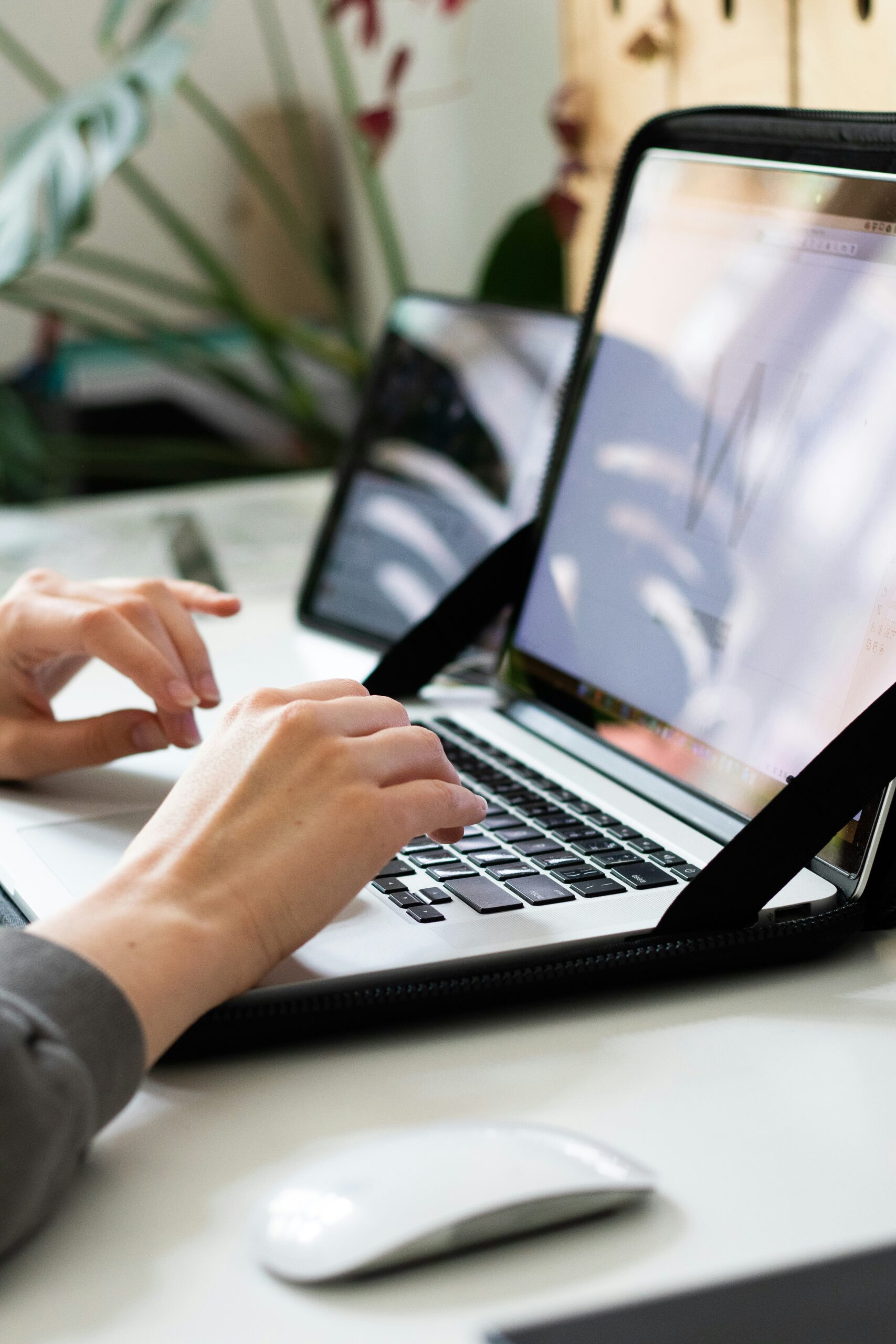 Seitenansicht eines aufgeklappten Laptops, auf dem zwei Hände in Arbeitsbereitschaft ruhen. Man erkennt ein geöffnetes Programm, auf dem der Großbuchstabe W mit Leitlinien dargestellt ist.